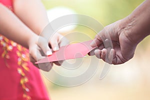 Parent give money in red envelope to little child girl