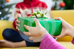 Parent giving Christmas gift box to asian child girl on Christmas celebration