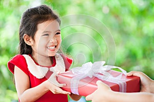 Parent giving Christmas gift to cute asian child girl