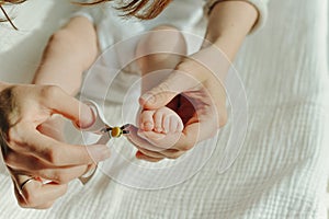 Parent hand holding scissors trimming child toenail