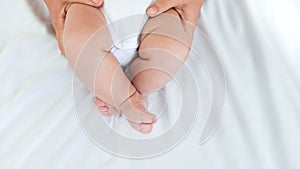 Parent hands holding newborn chubby legs on white background. Hand holding baby