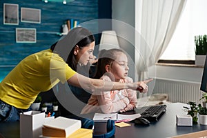 Parent helping daughter with mathematics homework using classroom e-learning platform