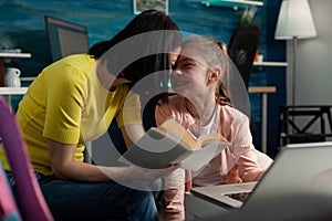 Parent helping little child with school homework sitting beside