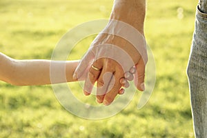 Parent holds the hand of a small child