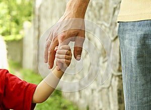 Parent holds the hand of a small child