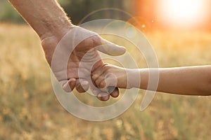 Parent holds the hand of a small child