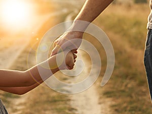 Parent holds the hand of a small child