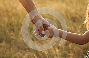 Parent holds the hand of a small child