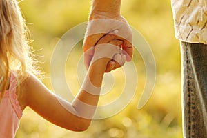 Parent holds the hand of a small child