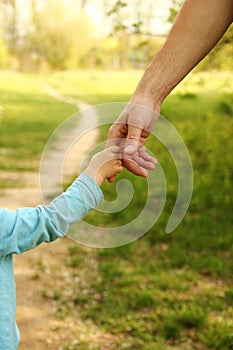 Parent holds the hand of a small child