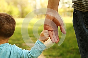 Parent holds the hand of a small child