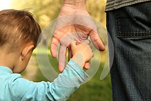 Parent holds the hand of a small child