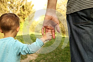 Parent holds the hand of a small child