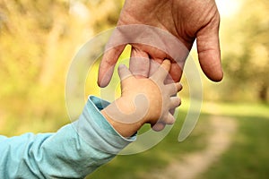 Parent holds the hand of a small child