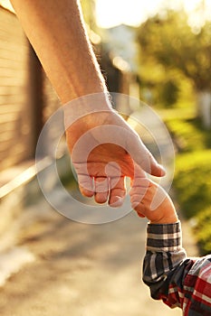 Parent holds the hand of a small child