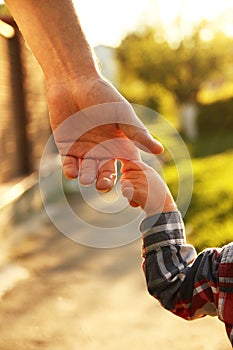 Parent holds the hand of a small child