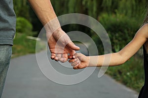 Parent holds the hand of a small child