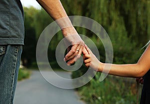 Parent holds the hand of a small child