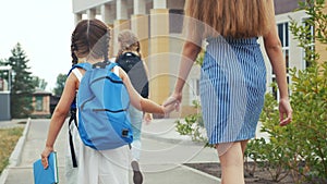 Parent leads to school child with backpack back view. kids go to school with backpacks education concept. mom leads