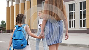 Parent leads to school child with backpack back view. Kids go to school with backpacks education concept. Mom leads