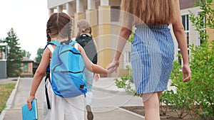 Parent leads to school child with backpack back view. kids go to school with backpacks education concept. mom leads