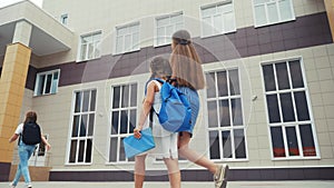 Parent leads to school lifestyle child with backpack back view. kids go to school with backpacks education concept. mom