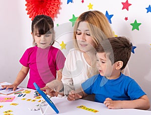 Parent learning and playing with kids. Mother or teacher painting or learning english letters with children.Homeschooling