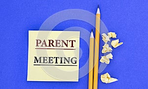 PARENT MEETING - word on note paper on blue background with pencils