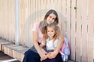 Parent mother taking child to school. Pupil girl of primary school go study with blue backpack outdoors. Back to school. First day