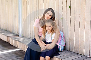 Parent mother taking child to school. Pupil girl of primary school go study with blue backpack outdoors. Back to school. First day