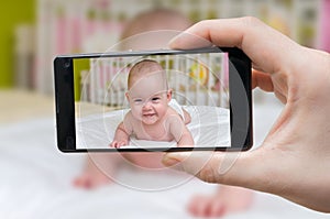 Parent is taking photo of a baby with smartphone photo