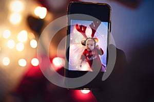 Parent taking photo of a baby with smartphone. Digital family memories