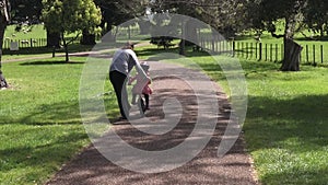 Parent teaching a child to how to ride bicycle without stabilisers in the park