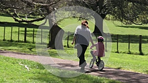 Parent teaching a child to how to ride bicycle without stabilisers in the park