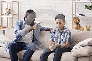 Parent Violence. Angry Black Father Scolding His Upset Innocent Son photo