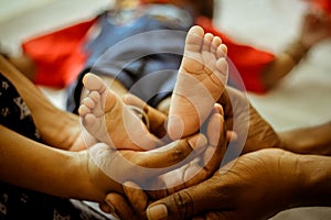 Parenthood Concept - Happy Mom and Dad are holding Baby feet on hands. Parents are holding the legs of a newborn baby