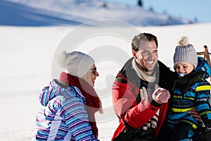 Parenthood, fashion, season and people concept - happy family with child on sled walking in winter outdoors