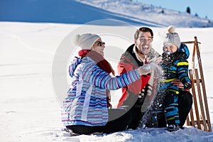 Parenthood, fashion, season and people concept - happy family with child on sled walking in winter outdoors