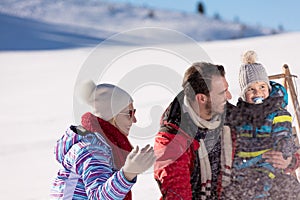 Parenthood, fashion, season and people concept - happy family with child on sled walking in winter outdoors