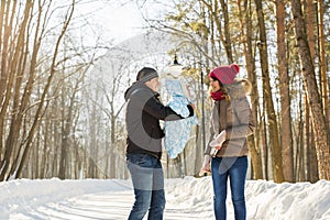 Parenthood, season and people concept - happy family with child in winter clothes outdoors