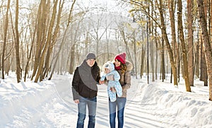 Parenthood, season and people concept - happy family with child in winter clothes outdoors