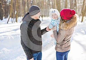 Parenthood, season and people concept - happy family with child in winter clothes outdoors