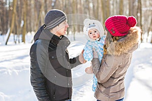 Parenthood, season and people concept - happy family with child in winter clothes outdoors