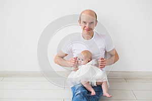 Parenting, family and fatherhood concept - Bald father hugging his little infant baby daughter on white background with