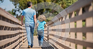 parenting and fatherhood. fathers day. happy father and son walking outdoor back view.