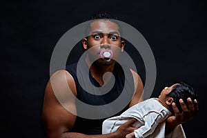 Parenting and love concept. african father with a pacifier holding infant