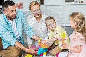 parents with adorable little kids playing with colorful blocks