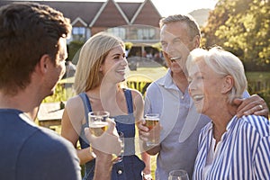 Parents With Adult Offspring Enjoying Outdoor Summer Drink At Pub