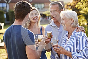 Parents With Adult Offspring Enjoying Outdoor Summer Drink At Pub