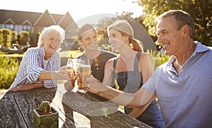 Parents With Adult Offspring Enjoying Outdoor Summer Drink At Pub